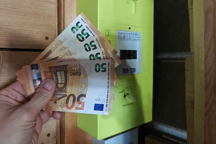 Des billets de 50 euros tenus devant un compteur électrique